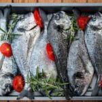 Pesce fresco su una griglia, pronto per essere cotto per preservare gli omega-3.